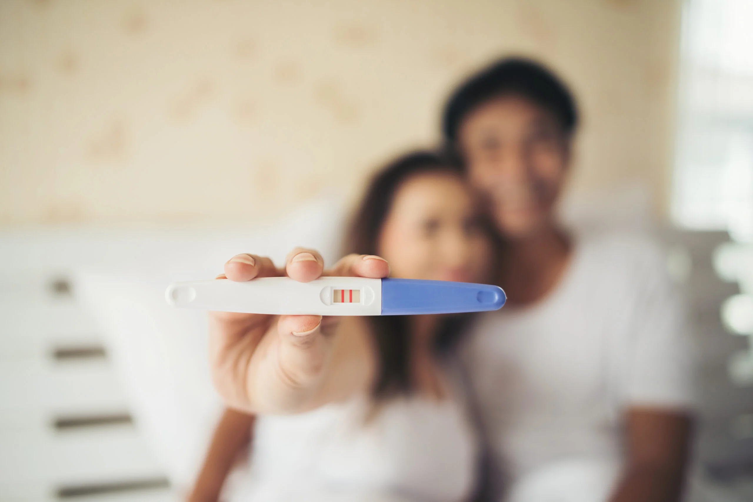 excited new parent hand show pregnancy test scaled