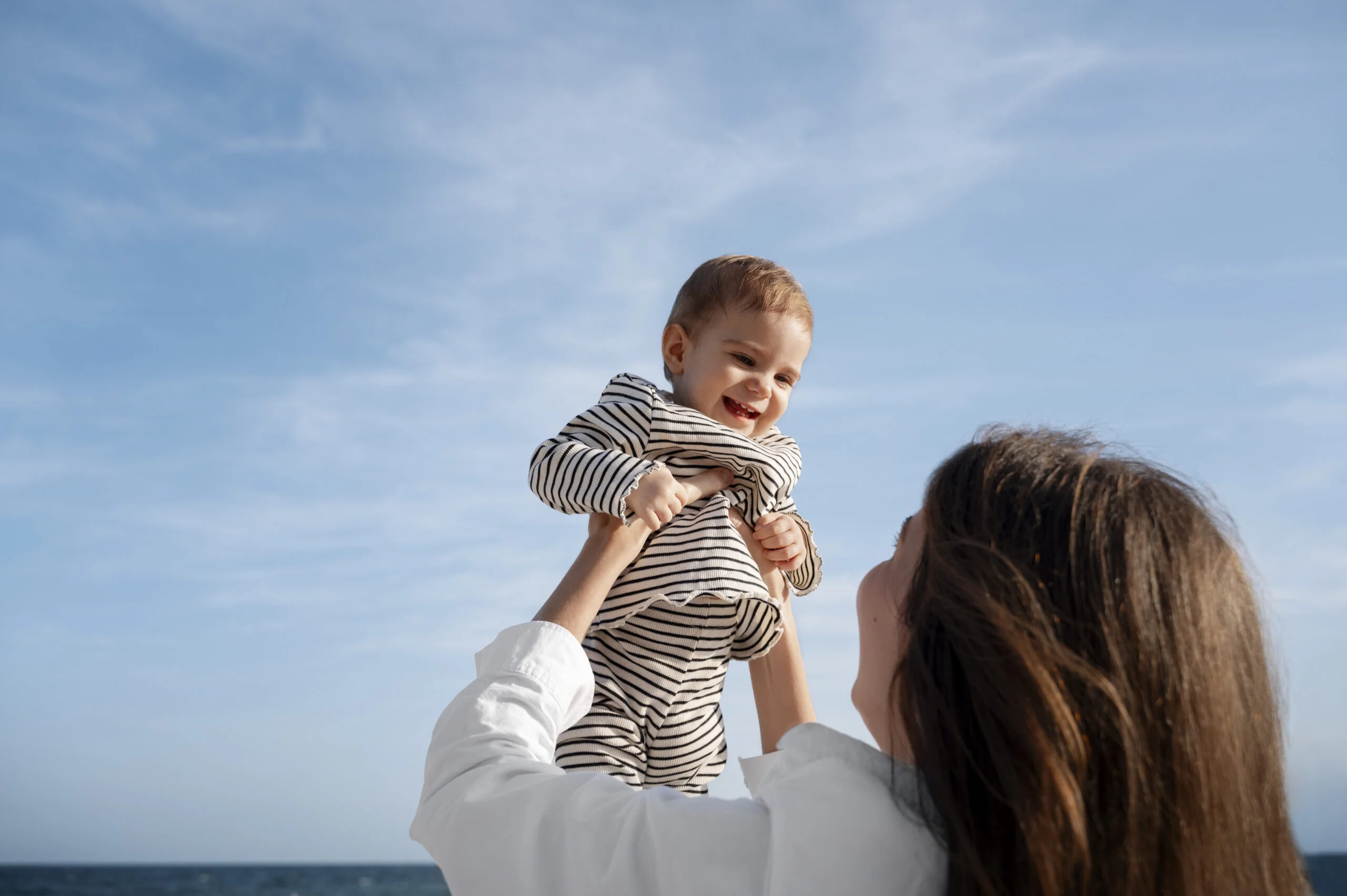 parent with baby beach sunset scaled
